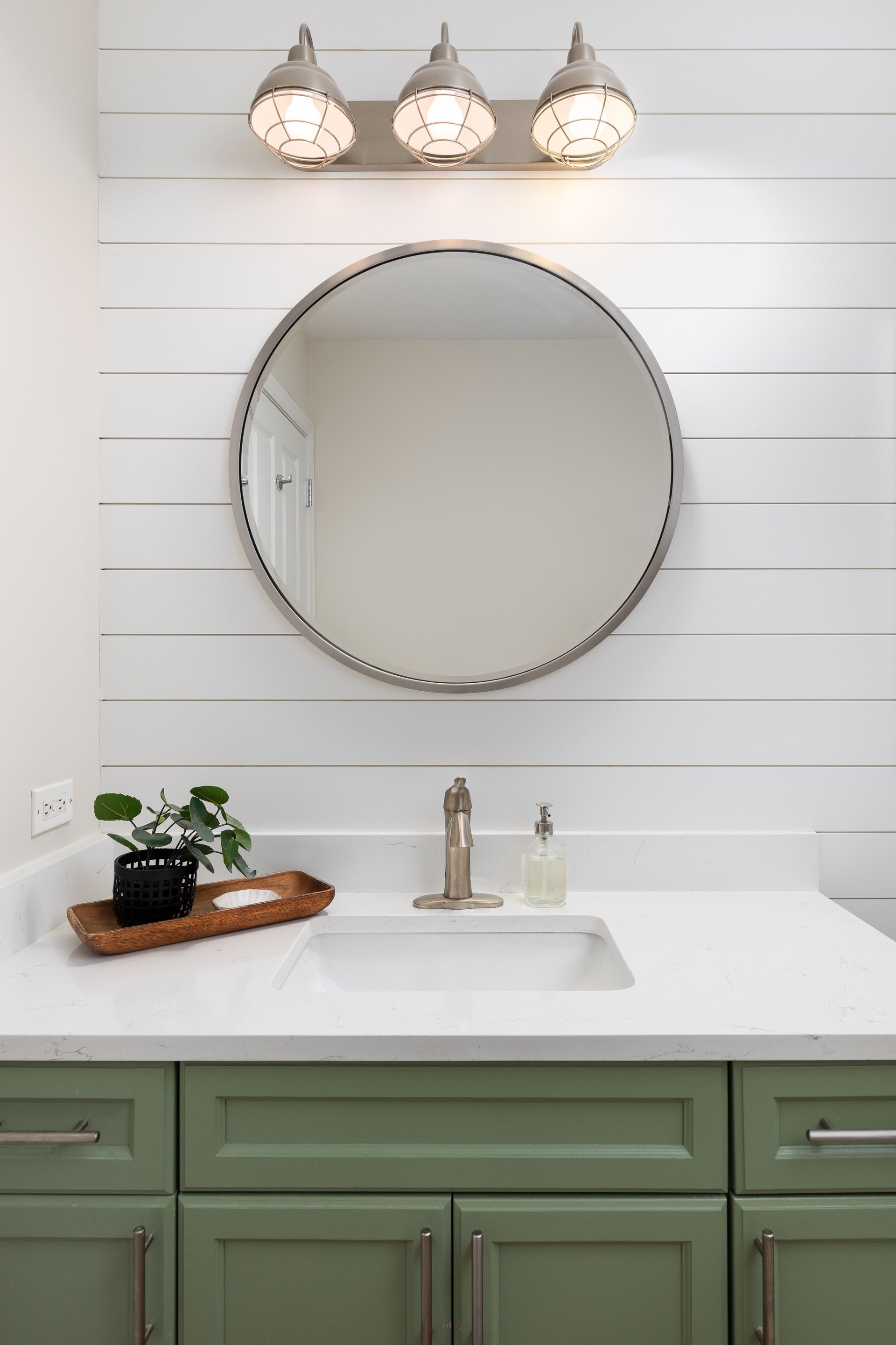 A bathroom with a green cabinet and white shiplap wall.